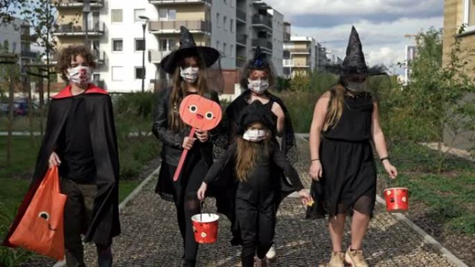 一群穿着黑色化装舞会的孩子正走在街上。每个人脸上都戴着医用口罩。covid19冠状病毒大流行期间的万