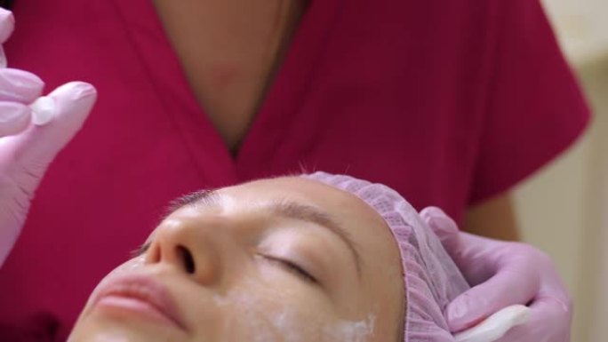 美容师在美容院中进行了恢复活力的面部注射程序，以收紧和抚平年轻女性面部皮肤上的皱纹