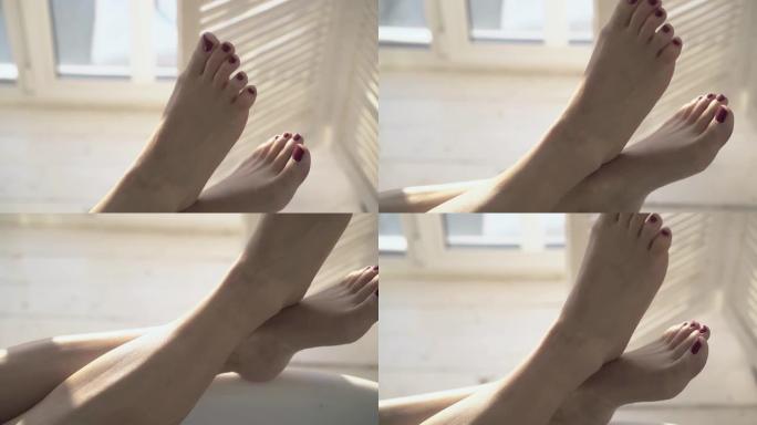 特写女人用优雅的红色修脚在浴缸上交叉脚