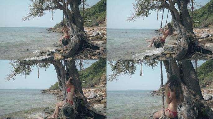 快乐的女孩坐在平静的海洋海滩上树边的老秋千上