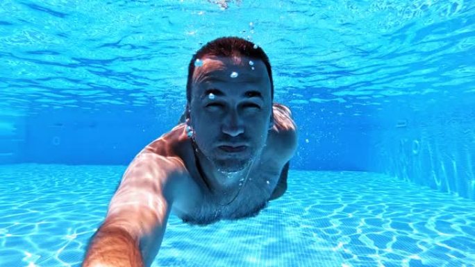 男子在游泳池里用水下摄像机游泳。