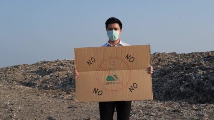 亚洲男子拿着纸作为志愿者或抗议。海报上为活动人士提供了关于有毒化学品危机的信息。志愿服务的概念，全球