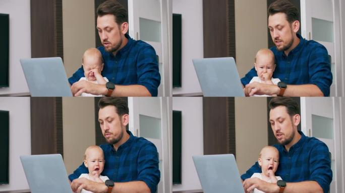 年轻的大胡子男人坐在家里的桌子上，拿着笔记本电脑，膝盖抱着可爱的婴儿，在键盘上写字，和婴儿说话。婴儿