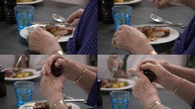 一名老年妇女用刀叉吃烤鸡晚餐