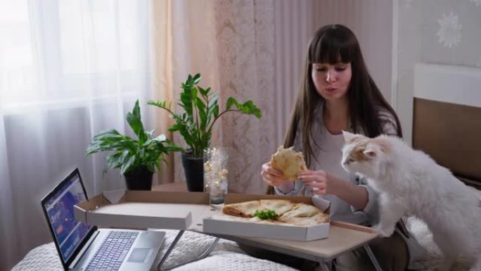 送餐，快乐的女孩顾客享受快餐披萨和她的宠物通过快递从坐在家里床上的笔记本电脑上的网吧送回家