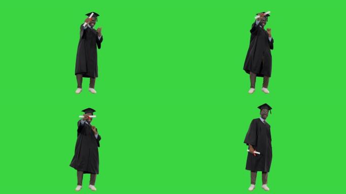 兴奋的非裔美国男学生穿着毕业长袍，放弃了文凭，并在绿色屏幕上摆姿势，色度键