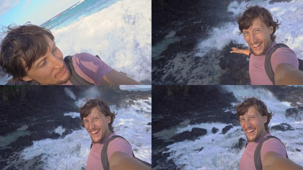 年轻人在黑色火山海滩上制作了自拍视频。海浪撞击岩石，导致天然喷泉的外观。慢动作镜头