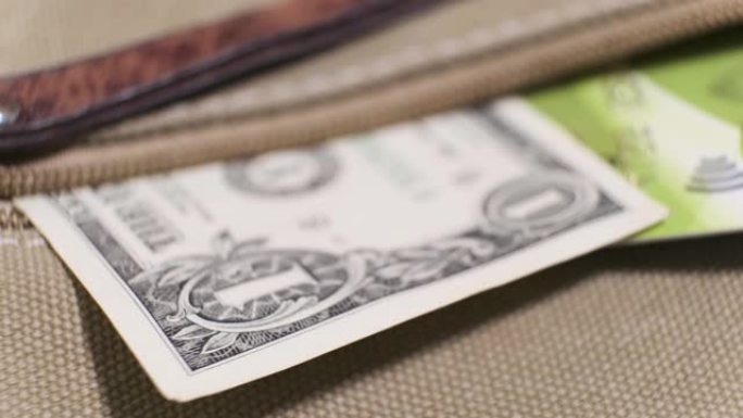 5美元的美国钞票和旋转桌子上的帆布袋口袋中的塑料信用卡。特写，浅景深