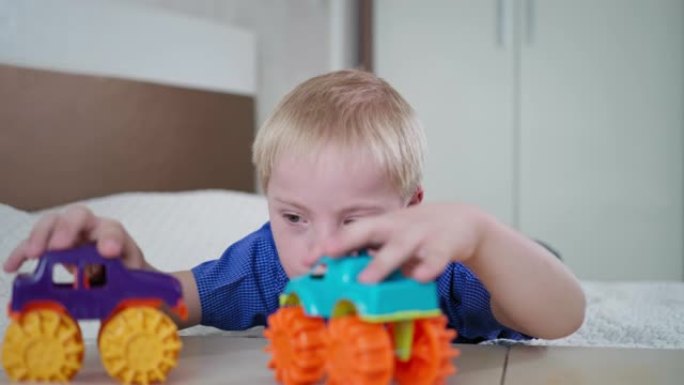 残疾儿童，唐氏综合症男孩的肖像在家里的房间里躺在床上玩汽车玩具