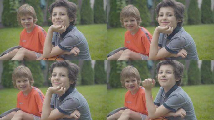 高加索小兄弟看着相机微笑的肖像。快乐的孩子们在公园户外休息。快乐的孩子享受周末与篮球