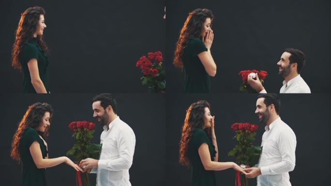 英俊的男人单膝站着，手里拿着戒指和玫瑰，向他的女人求婚。她答应了。