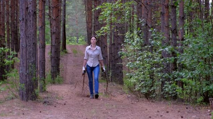 女人扛着砍倒的树木到森林侦察兵的营地寻找柴火，正面视图。