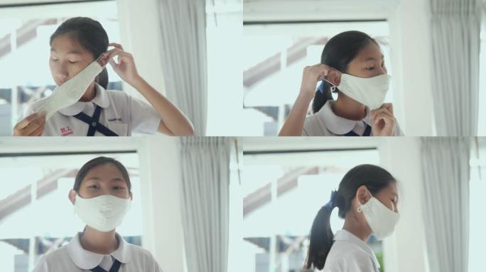 上学前在家窗户附近戴着口罩的亚洲女学生，新常态概念。