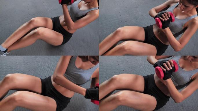 亚洲少女执行腹部肌肉在健身房使用哑铃，在健身房锻炼。