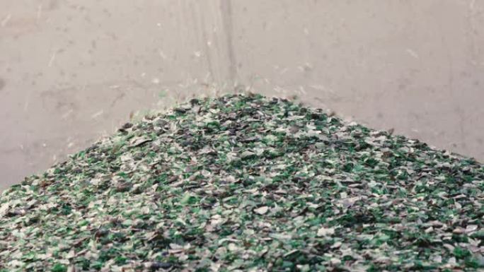 玻璃碎片从传送带上掉落在玻璃回收设施中的一堆上的细节。