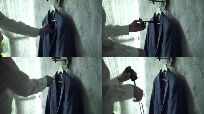 奥地利Kuchl - 2019年8月23日:新郎的早晨准备。男士的夹克和领结挂在木衣架上。新郎拿领结