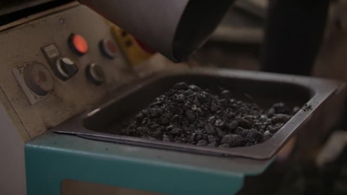 Slow-mo: 在沥青实验室中，将一个大金属桶从热的黑色沥青到小金属托盘中清空