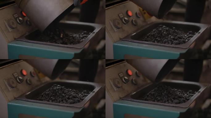 Slow-mo: 在沥青实验室中，将一个大金属桶从热的黑色沥青到小金属托盘中清空
