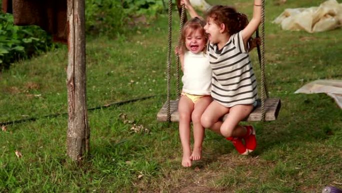 两个快乐的小女孩在后院的绳子上摇摆