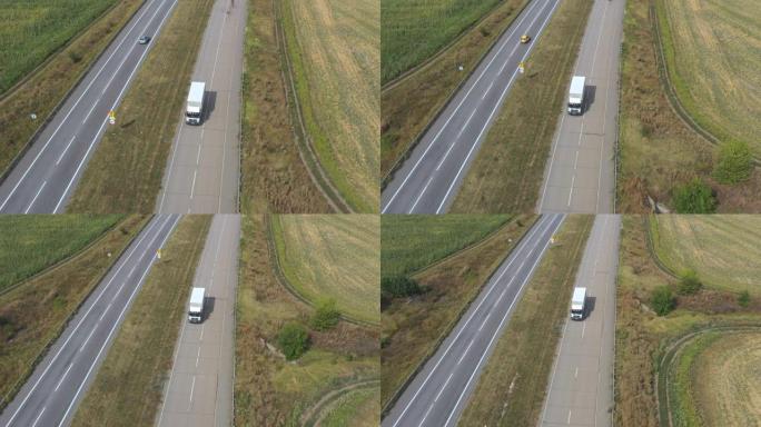 载货拖车在空旷的道路上行驶并运输货物的卡车的鸟瞰图。飞越送货卡车，沿着乡村的高速公路行驶。周围美丽的