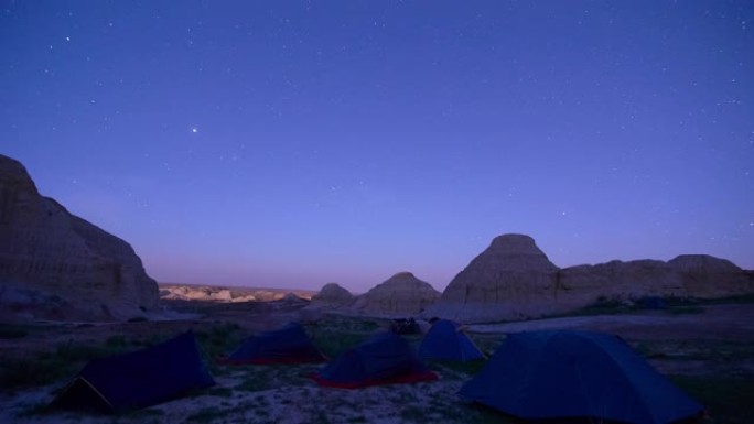 夜空中的星星和月升在沙漠山区的一个旅游营地上的运动。