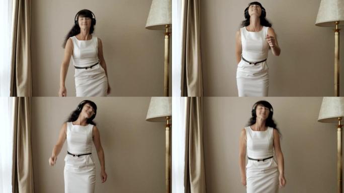 快乐的年轻女子跳舞，在房间里玩得开心，用无线耳机听音乐。商业女人喜欢跳舞，玩得开心。牙线舞蹈病毒，牙