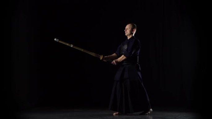 男性剑道战士在黑色背景上练习武术
