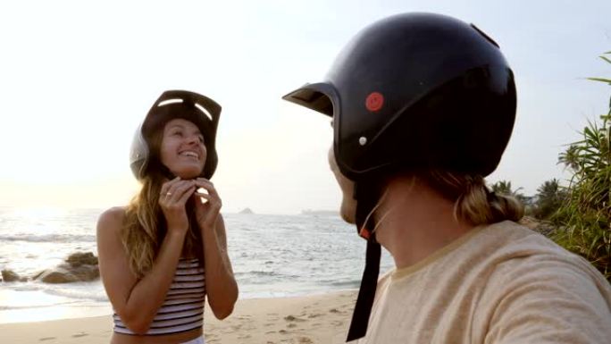 沙滩上情侣在骑踏板车前调整头盔的视点。人们在日落时分旅行，享受斯里兰卡的热带气候。慢动作