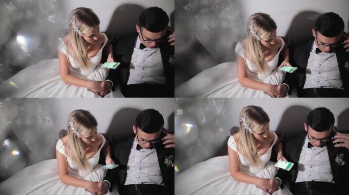 婚礼前，漂亮的年轻夫妇在酒店房间里，新郎在手机上聊天