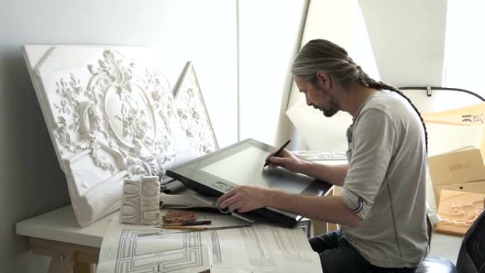 成熟的设计师将白色石膏造型与花卉装饰品复制到大型图形平板电脑上