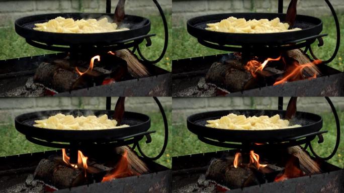 在铸铁锅里的烤架上烤土豆。铸铁煎锅，土豆放在明火上。