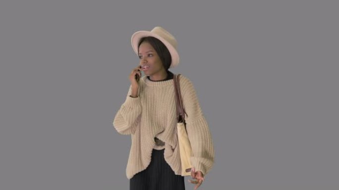 穿着针织毛衣和白帽子的沮丧的非洲裔美国妇女在电话上聊天，Alpha频道