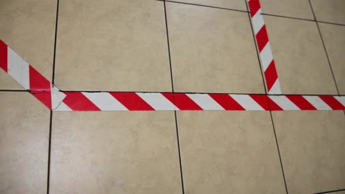 地板上贴有红色和白色的警告胶带，以保持社交距离。