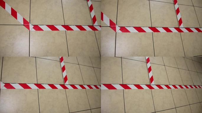 地板上贴有红色和白色的警告胶带，以保持社交距离。