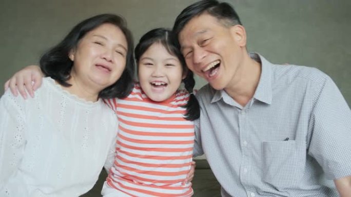 幸福亚洲祖母和祖父一起在床上玩耍，和他们的孙女一起笑。