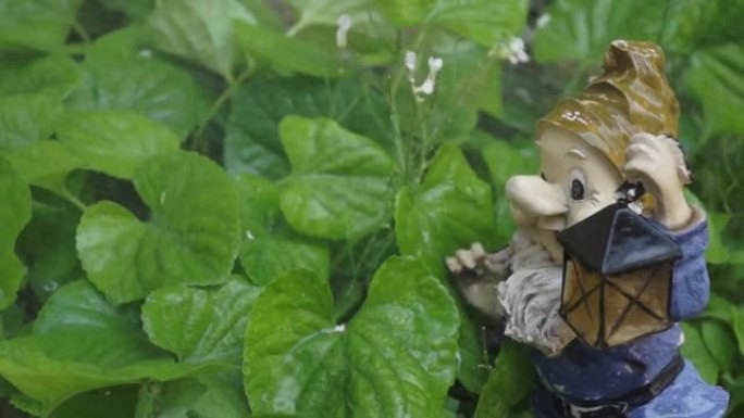绿叶花园侏儒的小雕像。喷水弄湿了侏儒的床单和小雕像