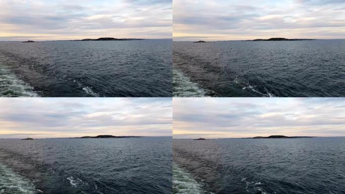 从船的船尾看海岸和海洋。在晴朗的天气下，船后的海浪。海鸥飞到船后。