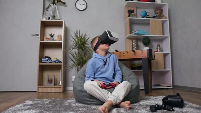 英俊的情感10岁男孩坐在充气沙发袋上用特殊的虚拟3d眼镜玩操纵杆游戏