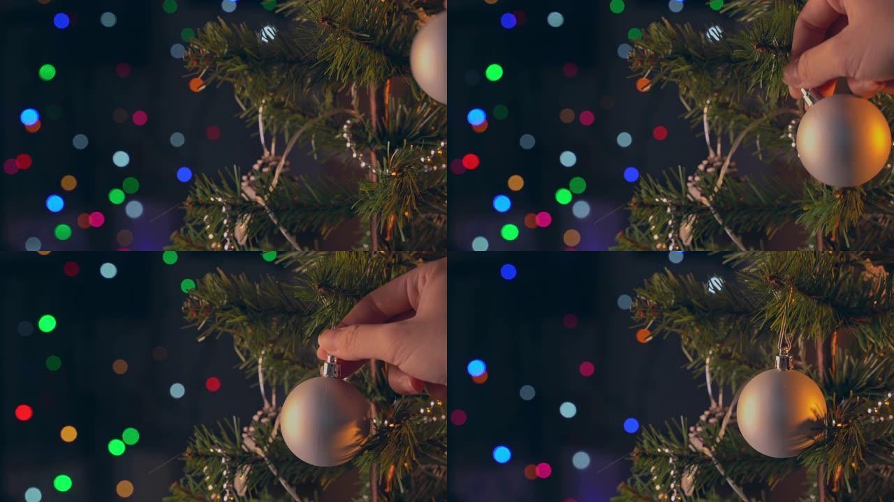 一名妇女在圣诞树树枝上悬挂圣诞节装饰，近距离拍摄，暗黑背景中闪烁着发光二极管灯。