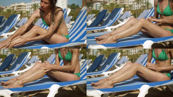 度假时免受阳光照射。年轻的黑发女人在苗条的身体上涂抹防晒霜，防晒霜或防晒霜的特写镜头。西班牙。4K