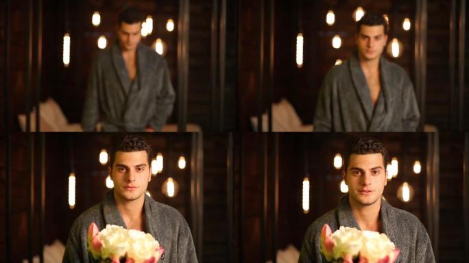 有魅力的男士穿着浴袍，对着镜头送花，然后露出胸膛。英俊的男人，在浪漫的夜晚拿着白玫瑰。情人节的概念