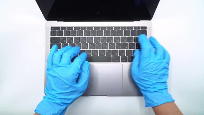戴上蓝色防护手套，在笔记本电脑键盘上书写，以4k分辨率特写视图。4k，UHD射击。网络通信、网上购物