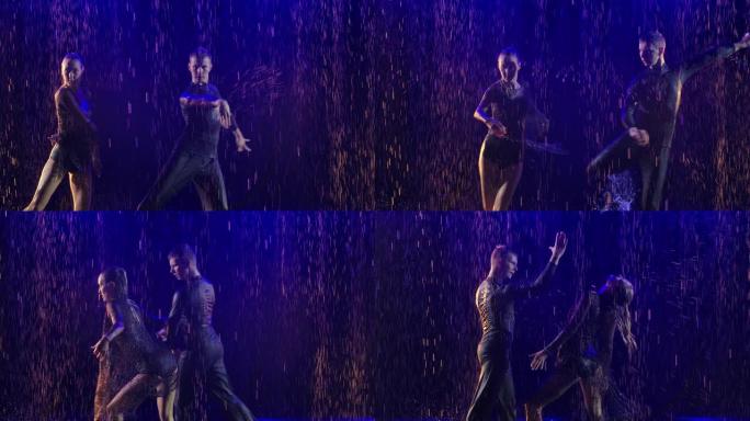 情侣在蓝色背光背景下在雨中跳舞jive。年轻的舞者沿着水面移动并产生许多飞溅。慢动作。特写