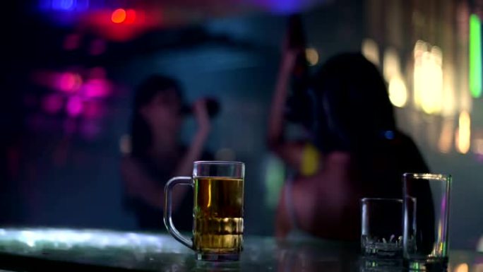桌上一杯啤酒，背景模糊，女人跳舞