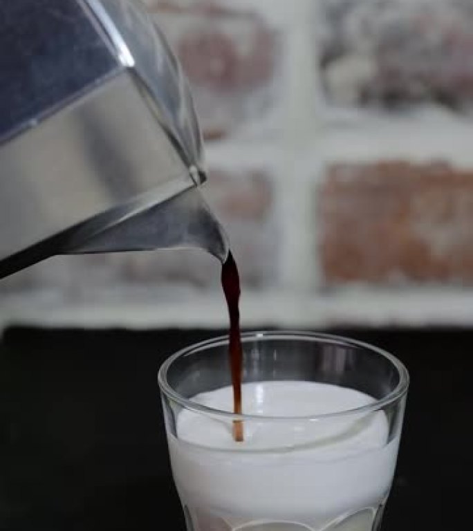 卡布奇诺咖啡，间歇泉咖啡机中的咖啡被倒入装有搅打牛奶的玻璃杯中。摩卡制作过程，特写，垂直布局视频，咖