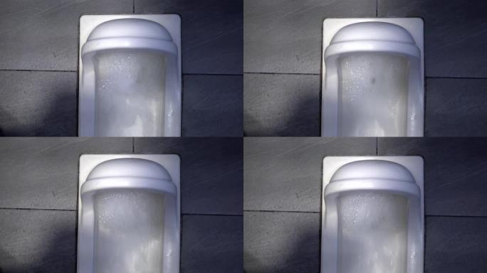 白色蹲式厕所在公共场所。水的冲动非常强烈。