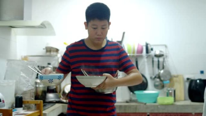 亚洲男孩拿起饭碗为家人摆桌，生活方式观念。