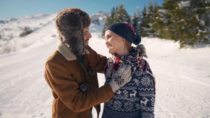 年轻人在雪山上拥抱和亲吻时，用围巾给女友热身