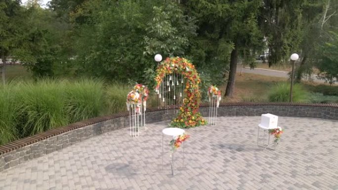 鸟瞰婚礼仪式，拱门装饰有秋叶和花朵，为客人准备的白色椅子，户外