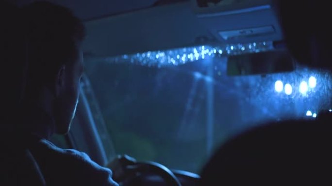 男子在夜雨路上驾驶汽车